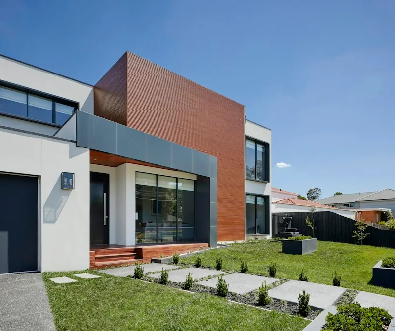 Modern two-story home with a white facade and timber-clad upper level